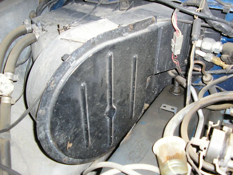 Close-up of a vehicle's heater box assembly with hoses and wiring