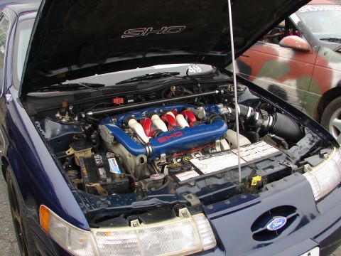 1992 Ford Taurus - The engine bay of a 1992 Ford Taurus SHO is displayed with the hood open, revealing its V8 engine.