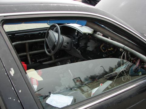 1992 Ford Taurus - Interior view of a 1992 Ford Taurus with a roll cage and stripped dashboard.