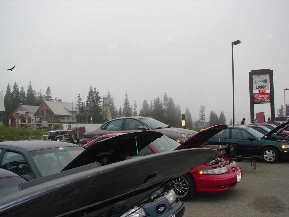 Ford sedans with hoods open at a foggy mountain car show near Summit Lodge sign