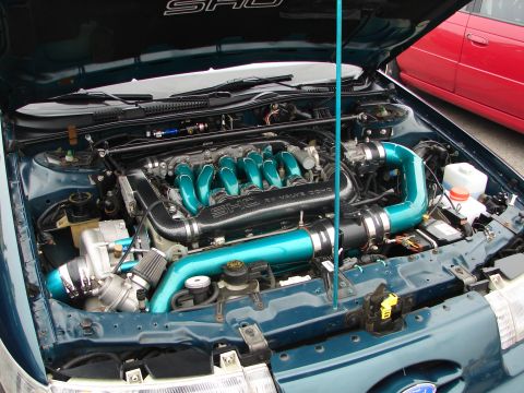1992 Ford Taurus - The engine bay of a teal 1992 Ford Taurus features custom teal piping and SHO badging.