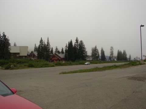 1992 Ford Taurus - A white sedan travels down a road in a foggy, mountainous area with several buildings visible.