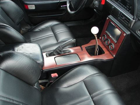 1992 Ford Taurus - Customized car interior features black leather seats and a modified center console with gauges and a stick shift.