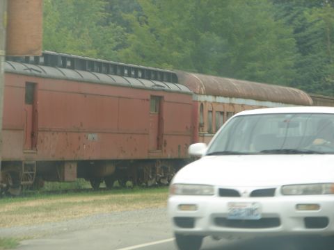 1992 Ford Taurus - A white sedan is parked next to an old red train car.