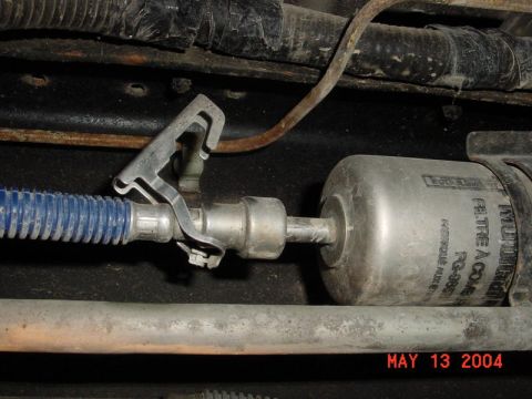 2007 Ford Mustang - Close-up of a fuel filter assembly, showing a blue hose and metal clamp. The date May 13 2004 is visible.