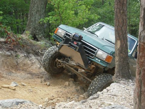 1995 Ford Bronco - This modified SUV is navigating a challenging off-road course with steep inclines and rocky terrain.