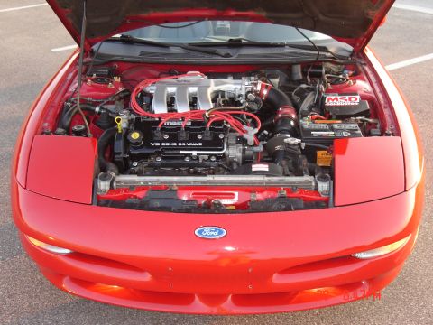 1993 Ford Probe - The engine bay of a red 1993 Ford Probe is displayed with the hood open, revealing the V6 DOHC 24-valve Mazda engine.