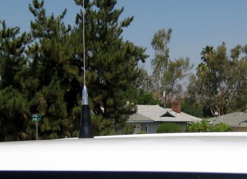 1996 Ford Bronco - A car antenna is visible against a backdrop of trees and suburban houses.