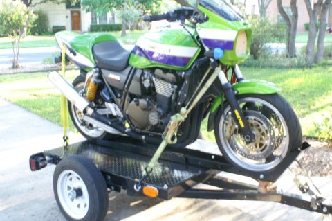 1981 Kawasaki Bayou - A sport motorcycle is secured to a trailer with yellow straps, ready for transport.