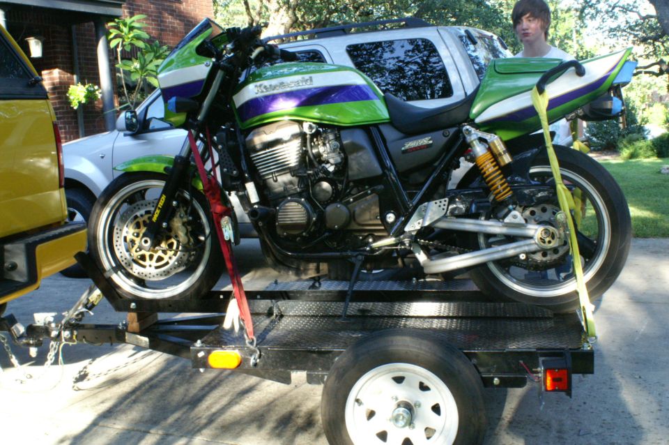 Green and purple Kawasaki motorcycle on a trailer, strapped down