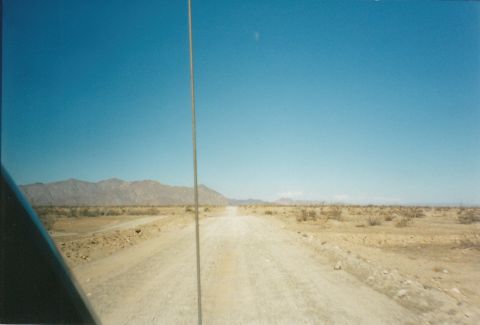 1994 Ford Bronco - Driving on a dirt road through a desert landscape with mountains in the distance.