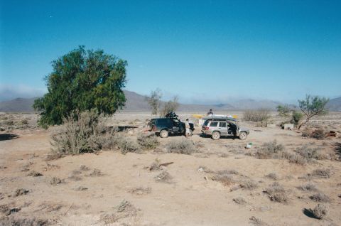 1994 Ford Bronco - Two SUVs are parked in a desert scene under a clear blue sky.