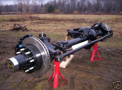 1996 Ford Bronco - A vehicle's front axle assembly, complete with disc brakes, is displayed outdoors on jack stands.