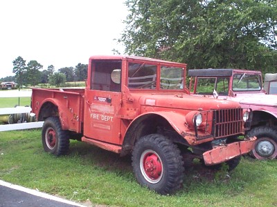 1991 Ford Bronco - A vintage red fire truck with "FIRE DEPT" visible on its door is parked outdoors next to another vehicle.