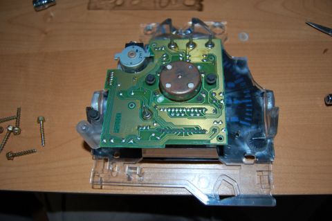 1985 Mercury Grand Marquis - Circuit board from a vehicle's instrument cluster, disassembled on a workbench with screws and tools nearby.