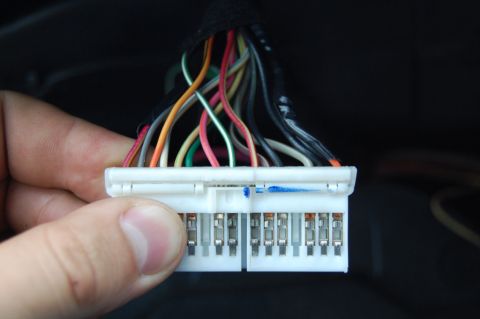 1985 Mercury Grand Marquis - A hand holds a white wiring harness connector with numerous colored wires extending from it.