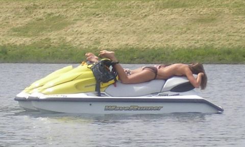 1994 Ford Probe - A person relaxes on a jet ski in the water with a grassy bank in the background.