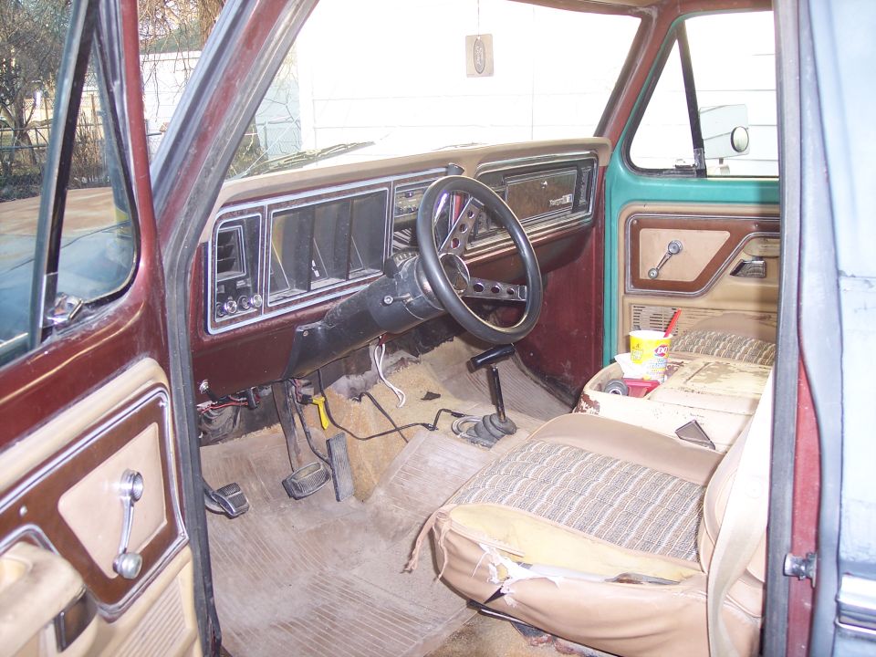 1979 Ford Bronco interior, showing dashboard, steering wheel, and torn seat