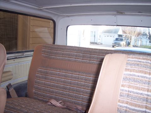 1979 Ford Bronco - View from inside a vehicle, showing the rear seats and a glimpse of the exterior including a truck and houses.