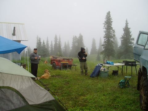 2000 Ford E350 - A misty morning at a campsite with a tent, trailer, and people gathered.