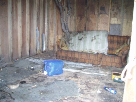 2000 Ford E350 - This scene depicts a neglected interior space with a worn couch and scattered items, suggesting abandonment.