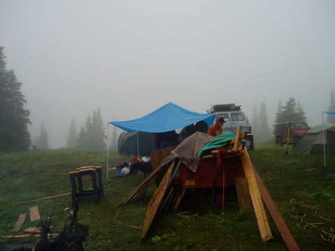 2000 Ford E350 - A foggy campsite scene with tents, a blue tarp, and two vehicles visible.