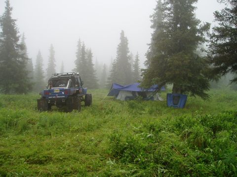2000 Ford E350 - An off-road vehicle sits in a misty field next to a campsite with tents.