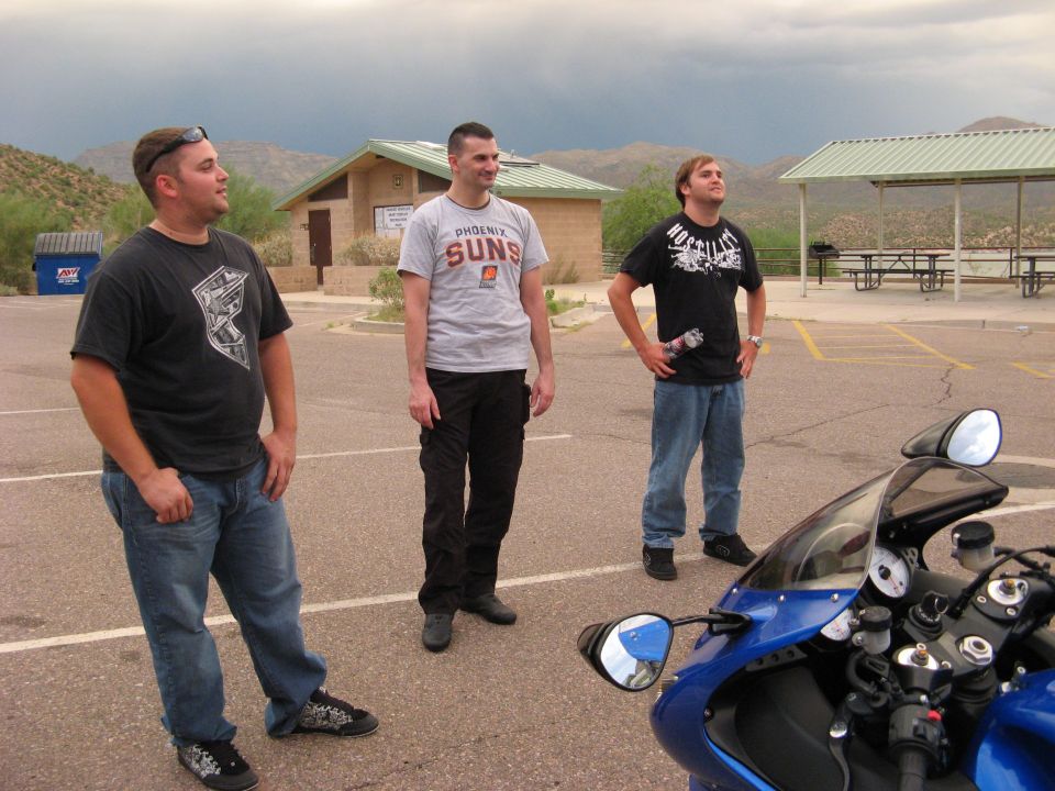 Blue Kawasaki Ninja motorcycle parked in a lot with three men.
