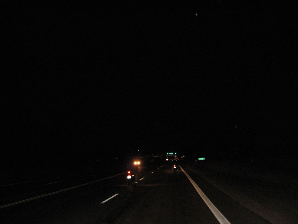 Two motorcycles on a highway at night.