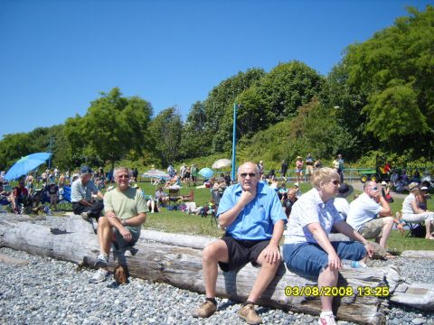 1989 Ford Bronco - A group of people are gathered outdoors on a sunny day, with many sitting on a large log in the foreground.