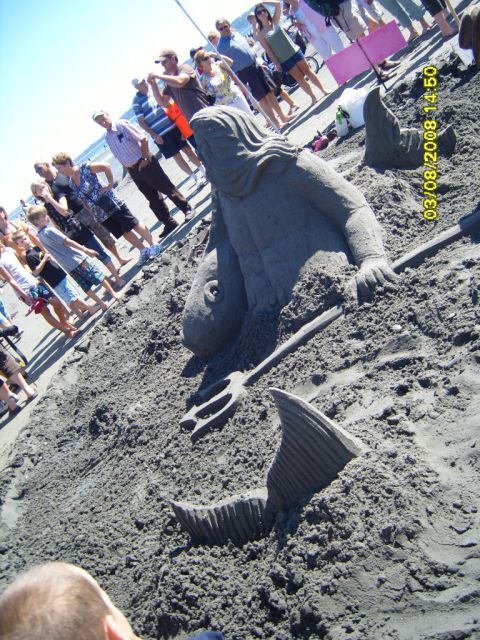 1989 Ford Bronco - A sand sculpture of a mermaid and a fish tail is on the beach, with a crowd of people in the background.
