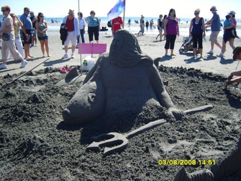 1989 Ford Bronco - A large sand sculpture of a mythical sea creature, possibly Poseidon, is displayed on a beach with people in the background. The sculpture…