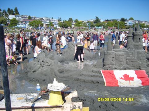 1989 Ford Bronco - A large crowd of people are gathered on a beach, admiring elaborate sandcastles. A Canadian flag is prominently displayed in front of one o…