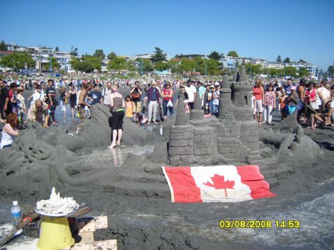 1989 Ford Bronco - A large sandcastle is being built on a beach with many people watching. A Canadian flag is placed in front of the sandcastle.