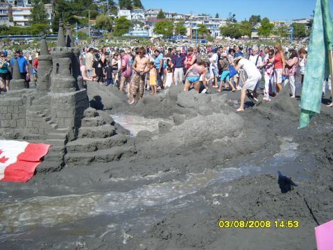 1989 Ford Bronco - A large sandcastle is displayed on a beach with many people gathered around it. A Canadian flag is placed at the base of the sandcastle.