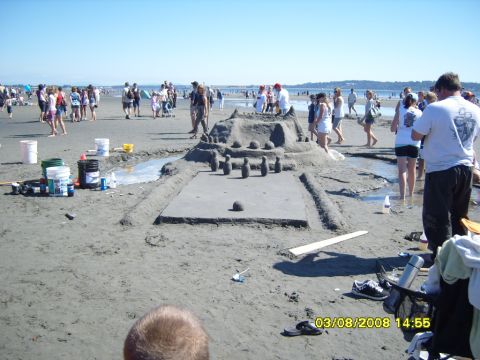1989 Ford Bronco - A sand sculpture of a bowling alley with pins and a ball is displayed on a beach with many people in the background. Buckets and tools are…