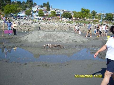 1989 Ford Bronco - A sandy beach scene with a sandcastle that has "WELCOME HILL" written on it. People are visible in the background and foreground.