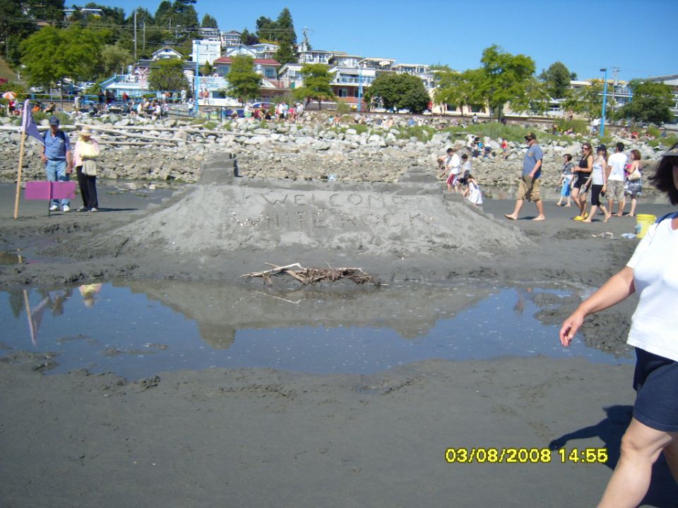 Beach scene with a sandcastle and people.