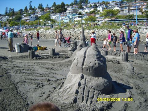 1989 Ford Bronco - A large sandcastle is the main focus of the image, with a beach and houses in the background. People are visible on the beach and in the di…