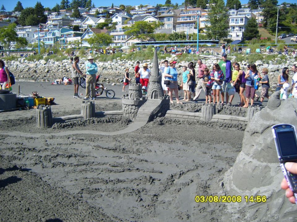 Sandcastle on a beach with people watching, date stamp 03/08/2008 14:56