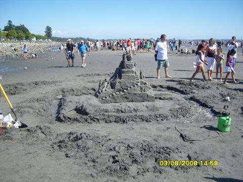 1989 Ford Bronco - A large sandcastle is the main focus of this beach scene, with many people in the background enjoying a sunny day. A shovel and a green spr…