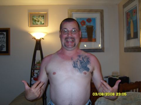 1989 Ford Bronco - A man with a tattoo on his chest stands in front of a lamp and framed pictures on the wall. The timestamp on the image reads 03/08/2008 23:…