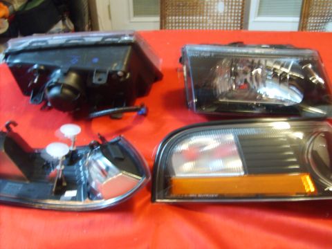 1993 Ford Crown Victoria - Multiple vehicle lights are laid out on a red surface, with one taillight clearly visible.