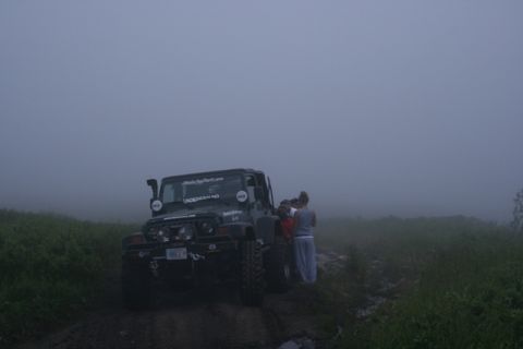 1990 Chevrolet Suburban - Jeep Wrangler on a foggy trail with a group of people gathered around.