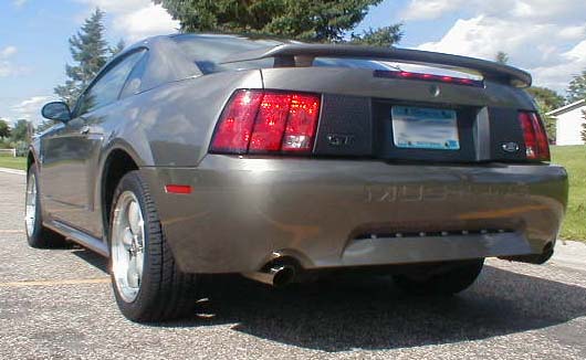 Rear view of a dark gray Ford Mustang GT coupe with spoiler and dual exhaust, parked outdoors
