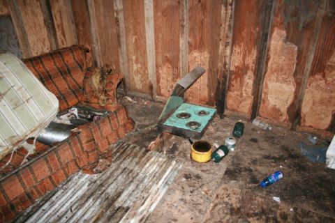 1990 Chevrolet Suburban - Interior scene shows a worn couch and a portable stove in a neglected space.