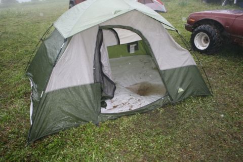 1990 Chevrolet Suburban - A tent is set up on a grassy field, with a car partially visible in the background.
