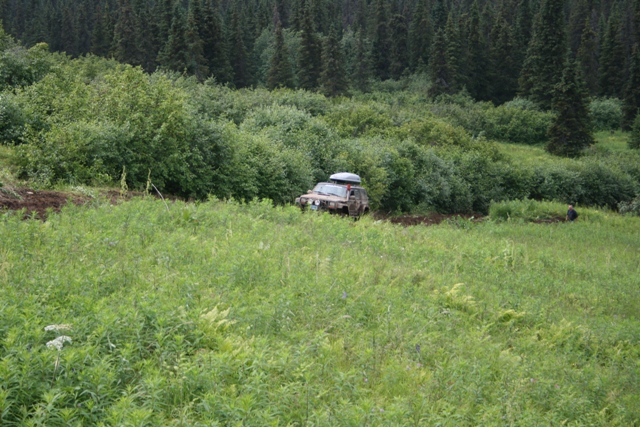 Tan 1990 Chevrolet Suburban off-roading with a roof-top carrier.