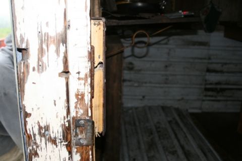 1990 Chevrolet Suburban - The interior of a structure shows a damaged wooden door frame with a visible latch mechanism.