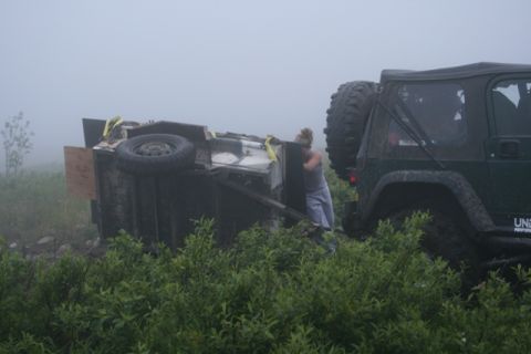1990 Chevrolet Suburban - A person attempts to right an overturned trailer with the assistance of a Jeep in a foggy, overgrown area.
